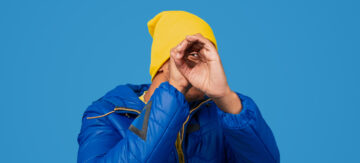 Man in yellow hat making telescope hands